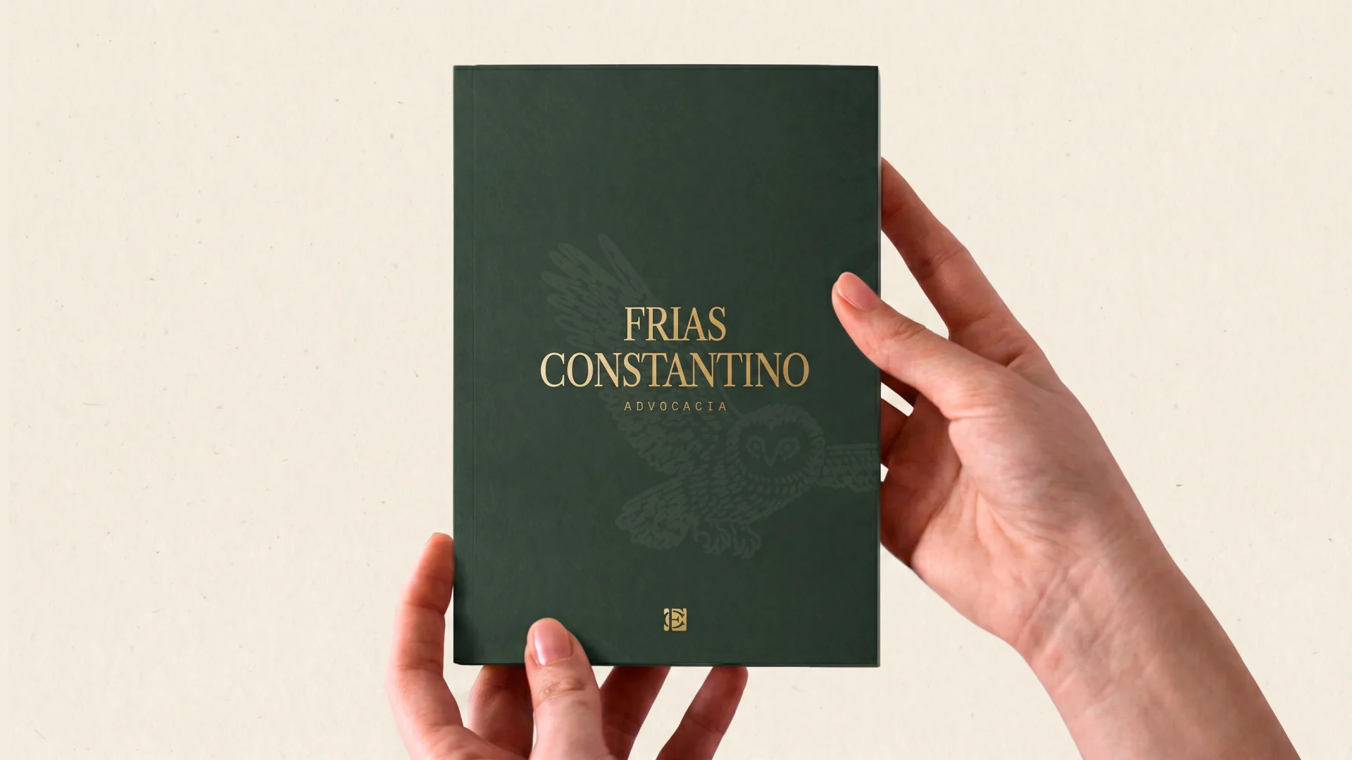 Hands holding a green brochure with the gold logo and the owl as a watermark