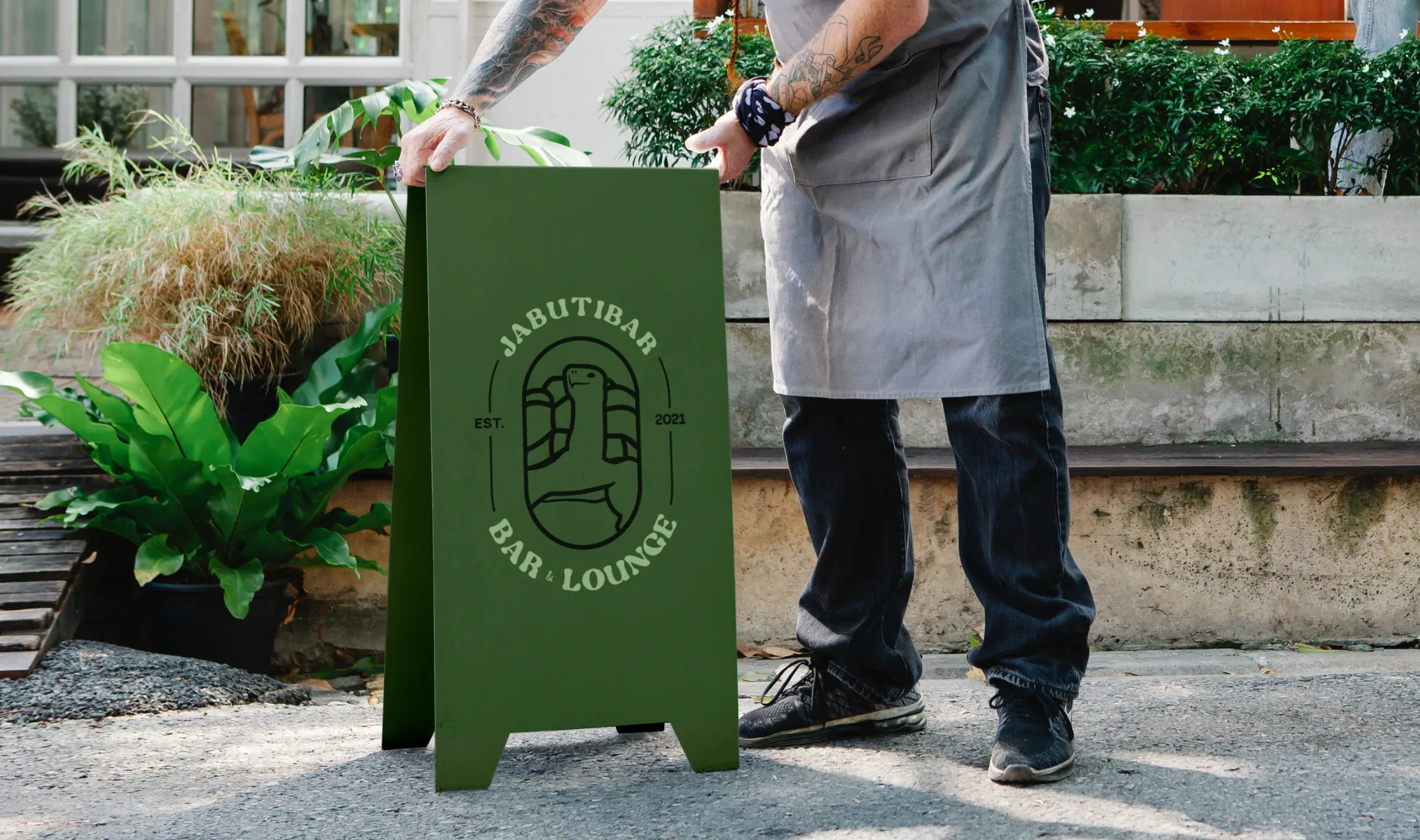 Green A-frame sign with the JabutiBar seal next to a waiter