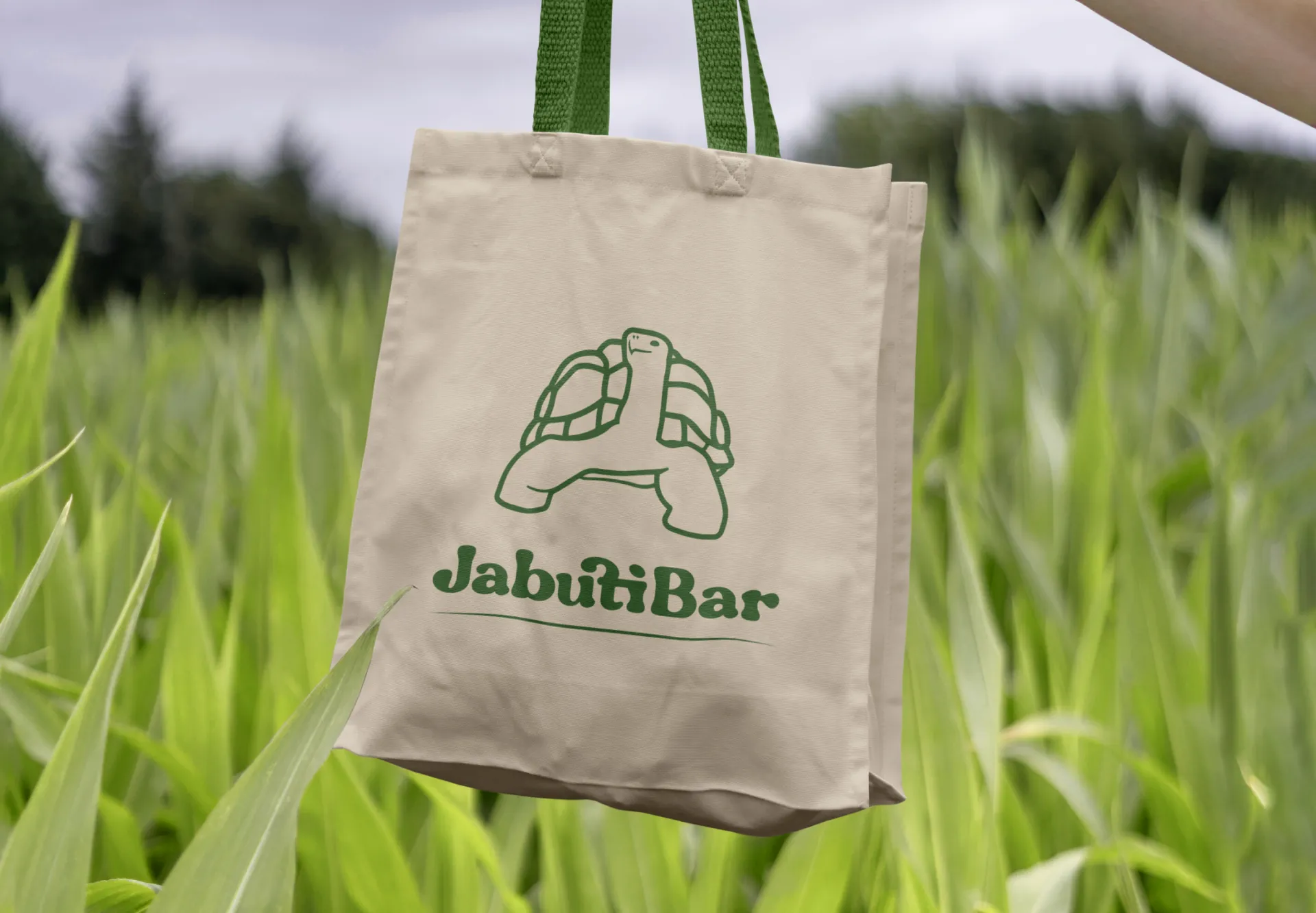 JabutiBar tote bag held in tall grass