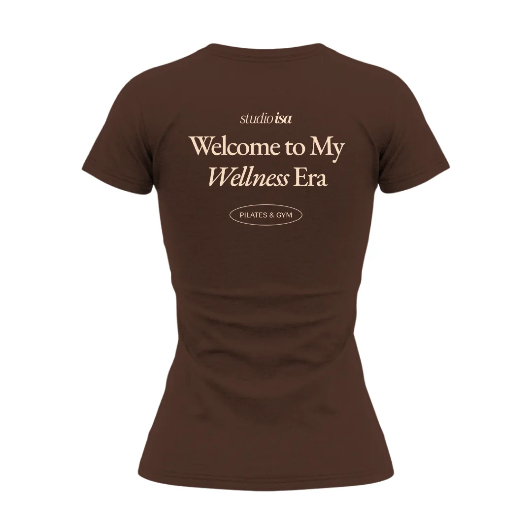 Back of a brown T-shirt with the line Welcome to My Wellness Era in beige