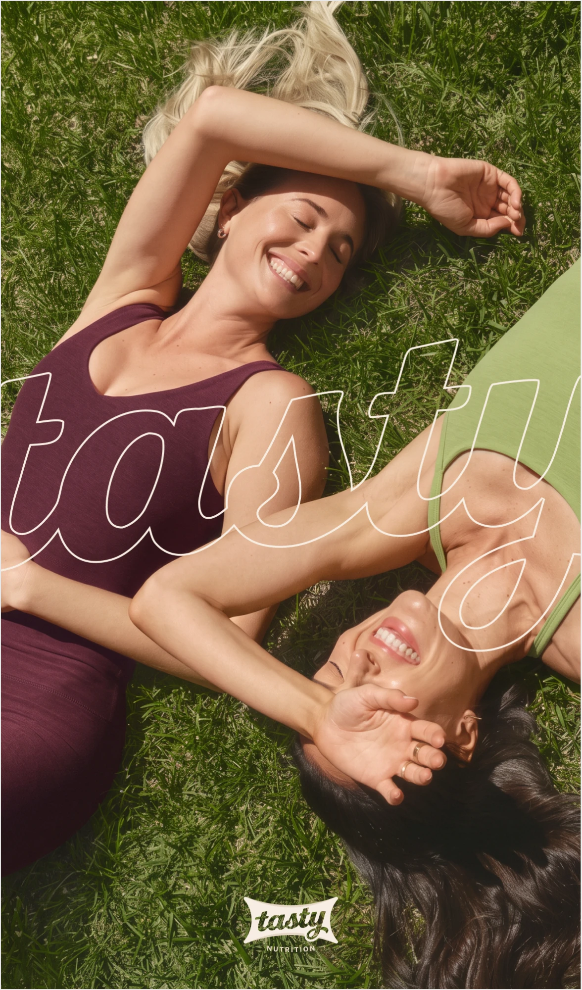 Outlined tasty lettering over two smiling women lying on the grass