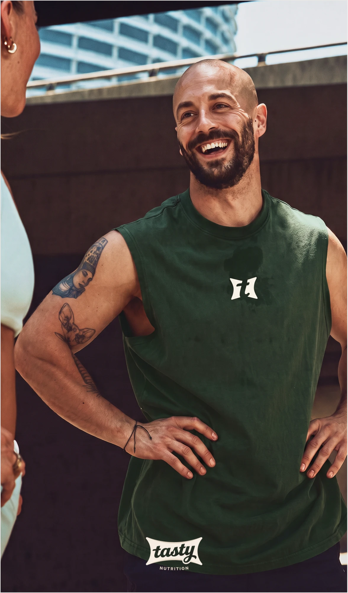 Smiling man in a green tank top with the brand icon on the chest