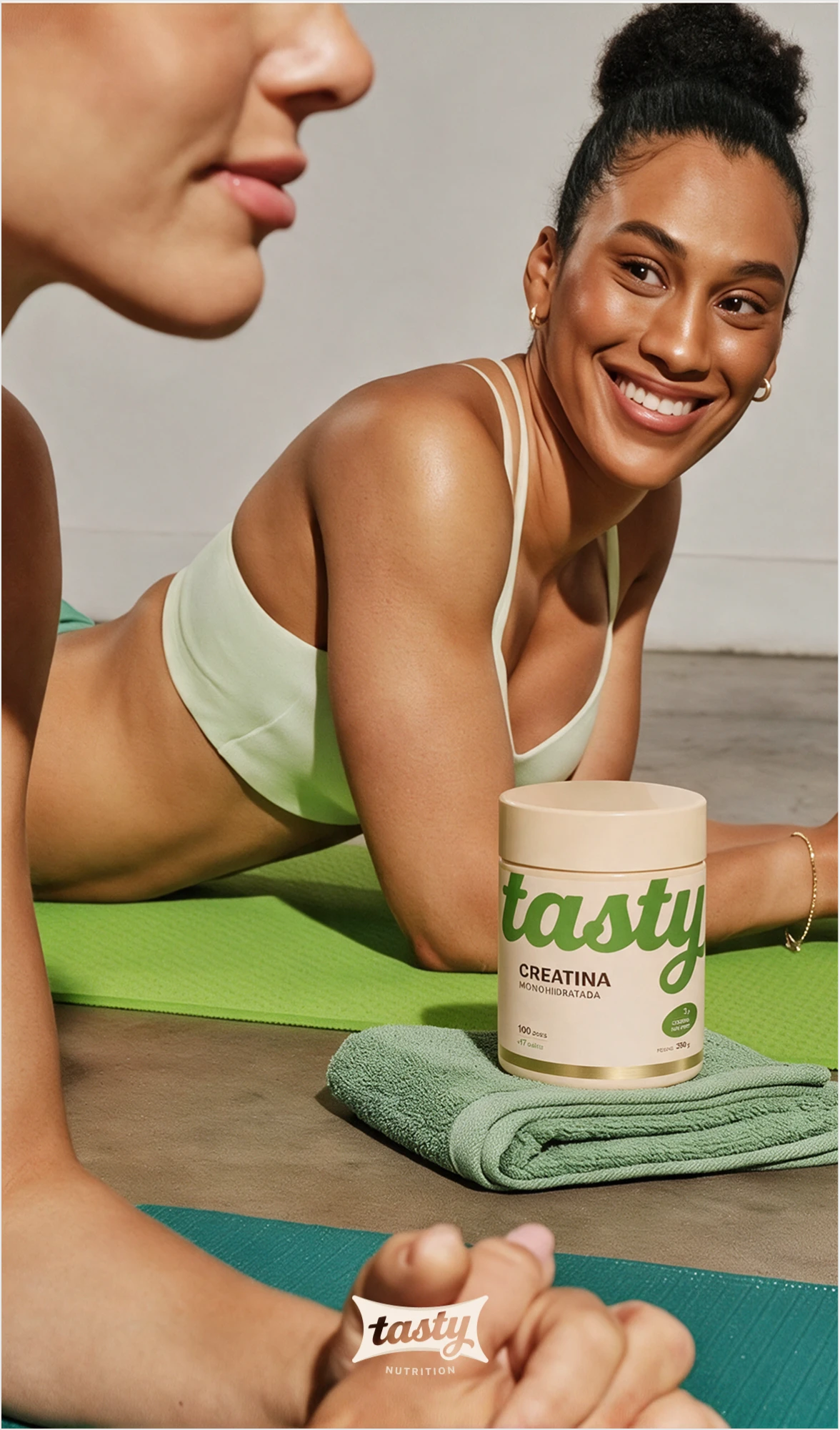 Smiling woman lying on a yoga mat, with the Tasty creatine jar on a green towel