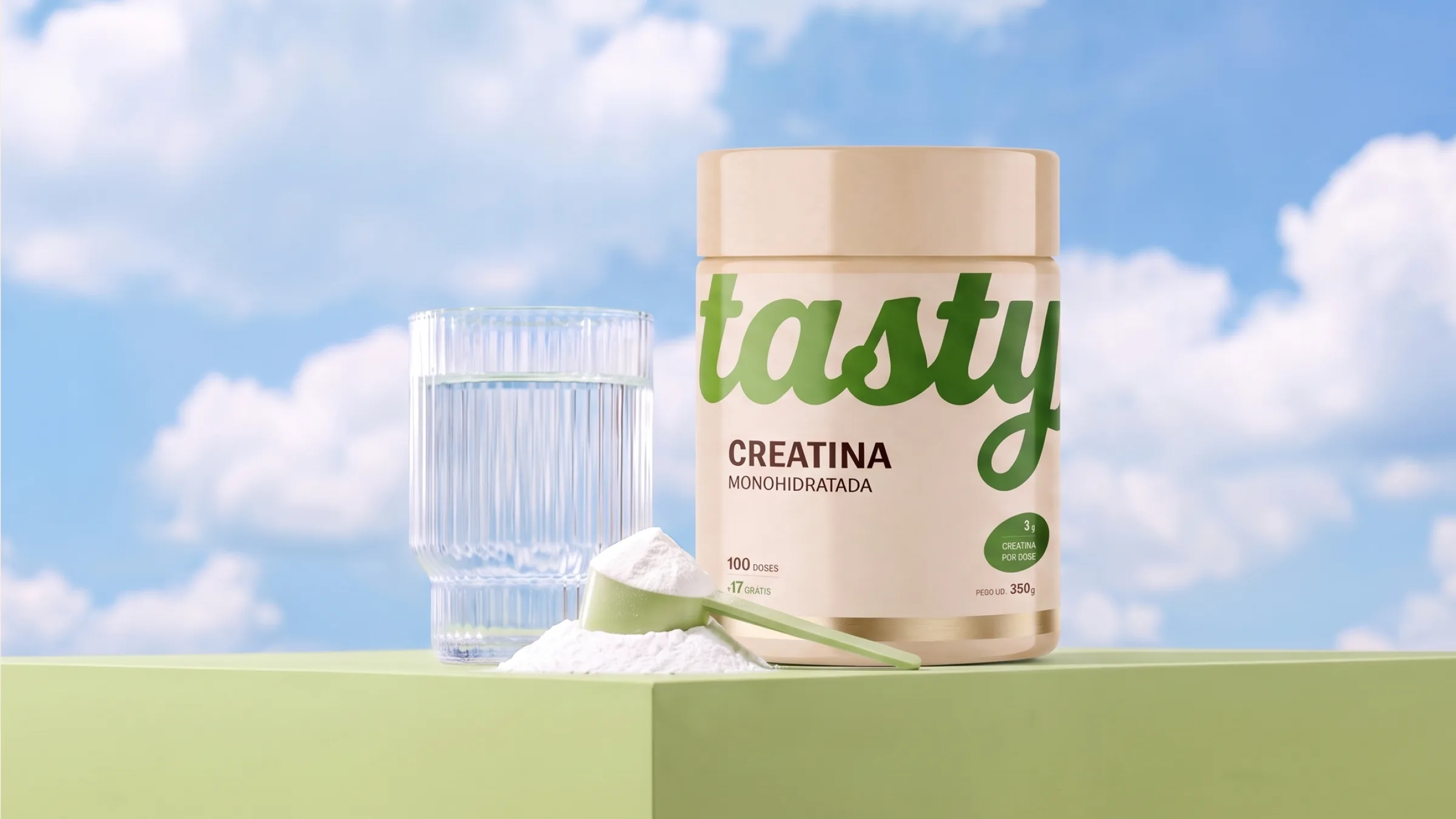 Tasty creatine jar with green lettering beside a glass of water and a scoop, on a green cube against a blue sky